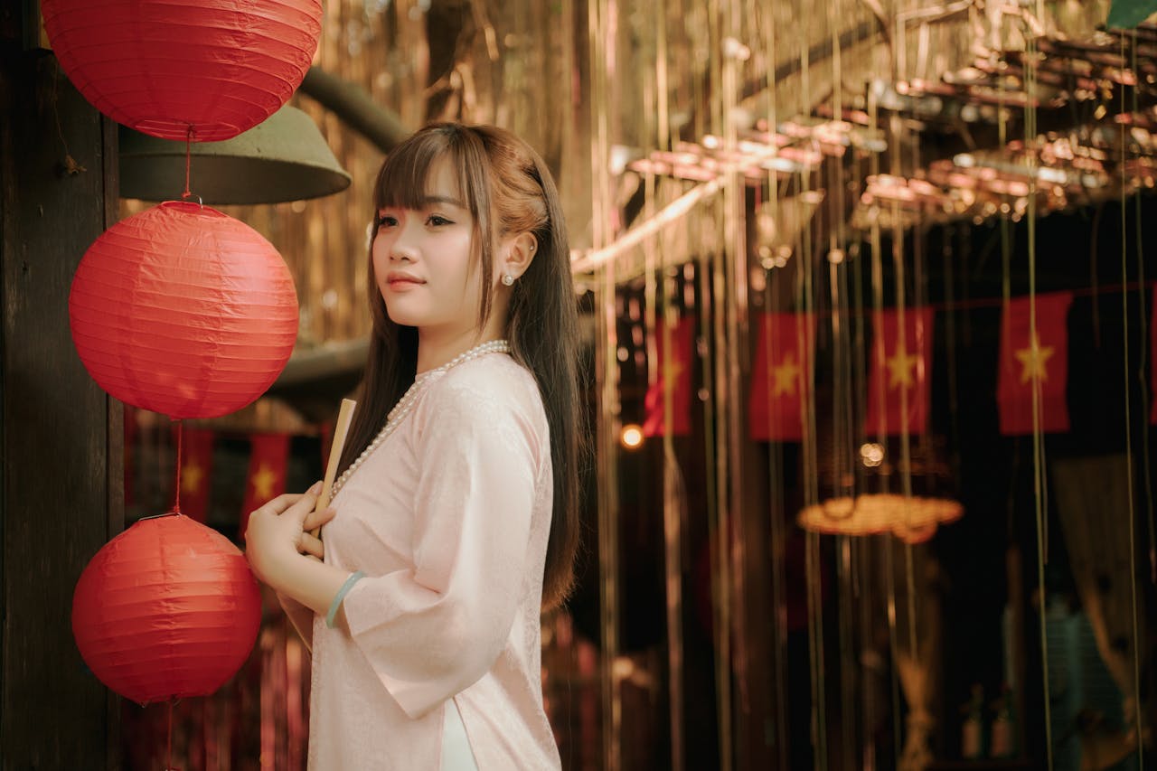 A young woman in traditional attire poses with red lanterns, capturing festive spirit.